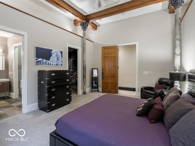 carpeted bedroom featuring ensuite bath, ceiling fan, and beamed ceiling