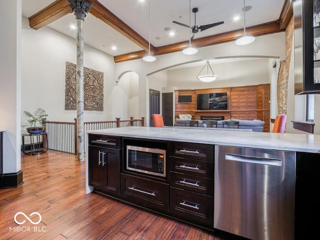 kitchen featuring ceiling fan, hanging light fixtures, beamed ceiling, dark hardwood / wood-style floors, and appliances with stainless steel finishes