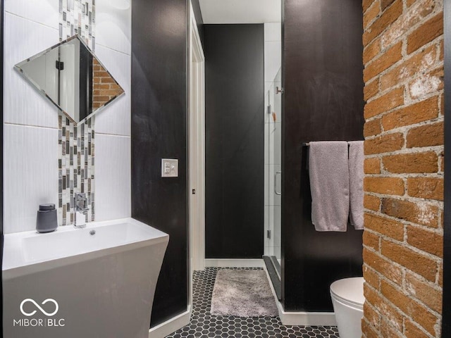 bathroom featuring tile patterned flooring, an enclosed shower, toilet, and brick wall