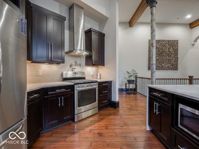 kitchen featuring wall chimney range hood, tasteful backsplash, beamed ceiling, dark hardwood / wood-style floors, and appliances with stainless steel finishes