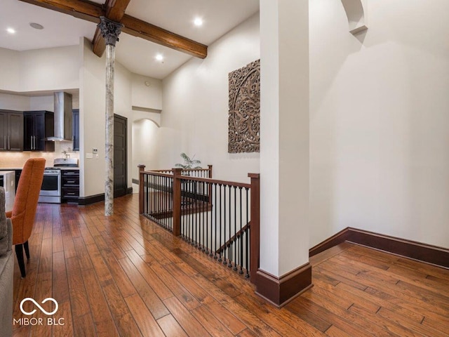 hallway featuring beam ceiling, dark hardwood / wood-style flooring, and a towering ceiling