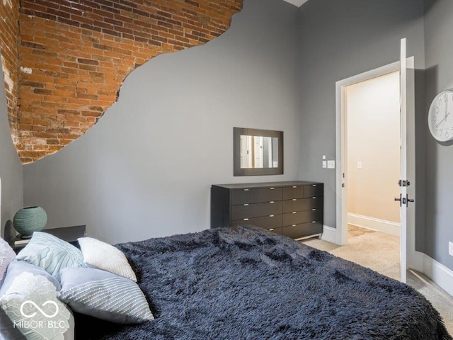 bedroom featuring light carpet, brick wall, and a high ceiling