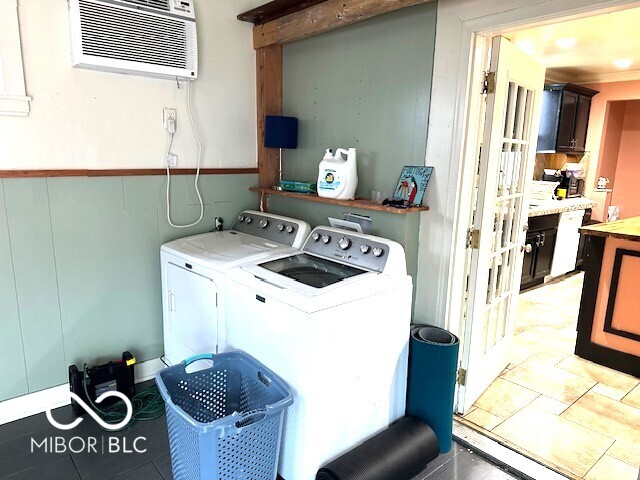 washroom with an AC wall unit, washer and clothes dryer, and ornamental molding