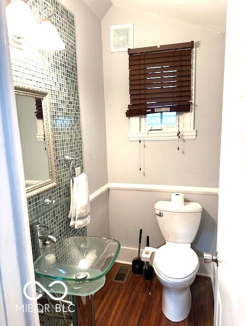 bathroom featuring backsplash, vaulted ceiling, sink, hardwood / wood-style floors, and toilet