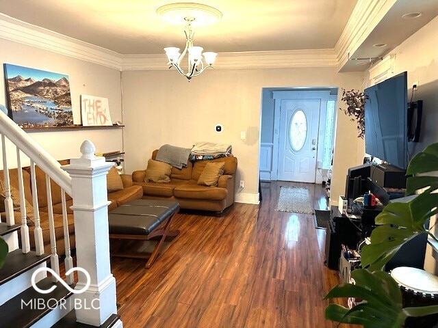 living room with hardwood / wood-style floors, ornamental molding, and a notable chandelier