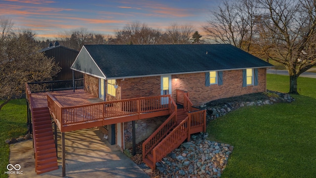 back house at dusk featuring a lawn and a deck