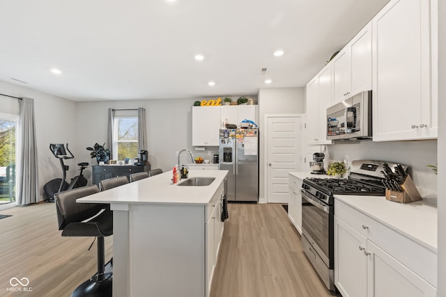 kitchen with stainless steel appliances, white cabinetry, a wealth of natural light, and sink