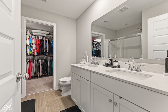 bathroom with vanity, toilet, and a shower with door