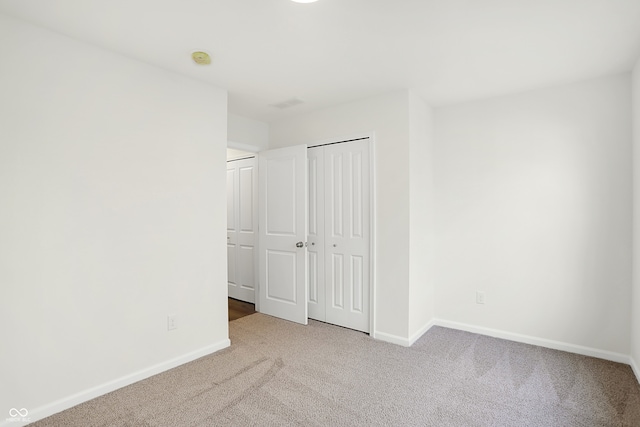 unfurnished bedroom with light carpet and a closet