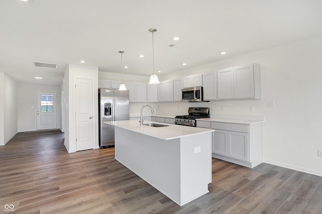 kitchen with an island with sink, stainless steel appliances, light hardwood / wood-style flooring, and sink