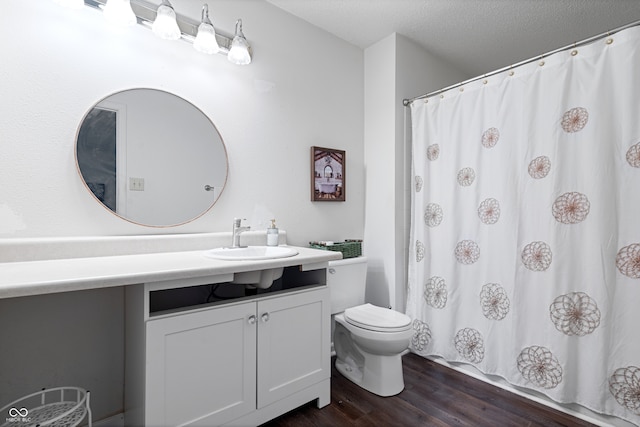 bathroom featuring a shower with curtain, vanity, a textured ceiling, hardwood / wood-style flooring, and toilet