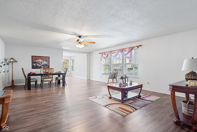 living room with ceiling fan, dark hardwood / wood-style flooring, and a textured ceiling