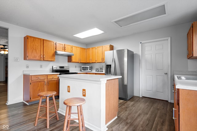 kitchen with a center island, sink, stainless steel appliances, dark hardwood / wood-style floors, and a breakfast bar