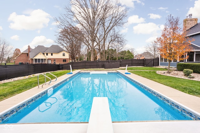 view of swimming pool with a lawn and a diving board