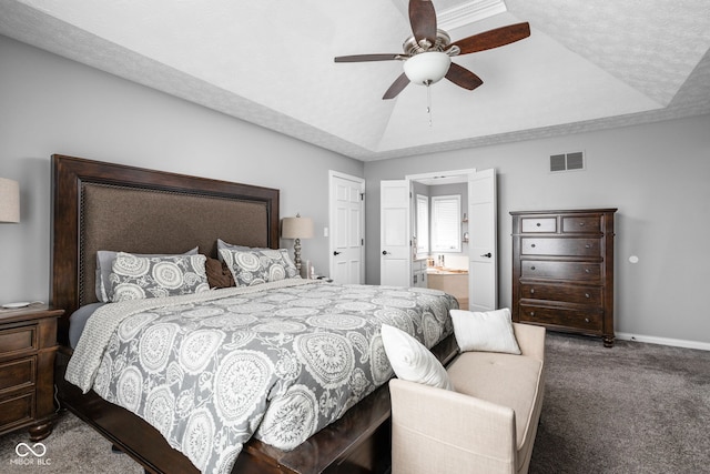 bedroom featuring carpet flooring, ceiling fan, a textured ceiling, connected bathroom, and a tray ceiling