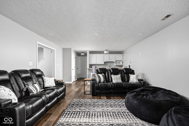 living room with a textured ceiling and dark hardwood / wood-style floors