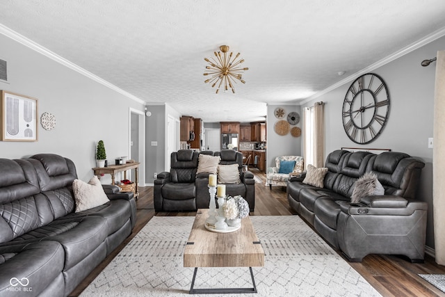 living room with a textured ceiling, dark hardwood / wood-style floors, an inviting chandelier, and ornamental molding