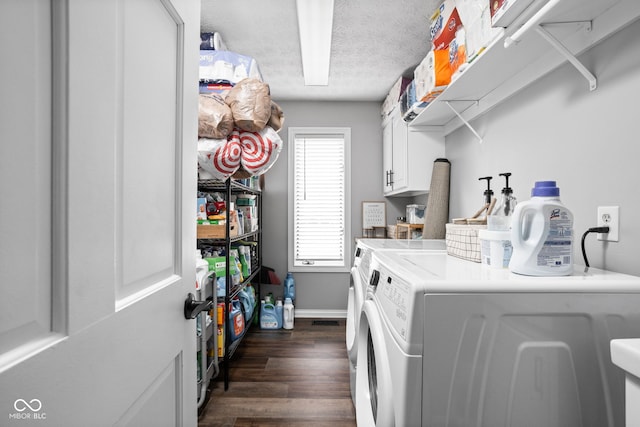 clothes washing area featuring a textured ceiling, washer and dryer, cabinets, and dark hardwood / wood-style floors