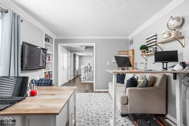 office area featuring hardwood / wood-style flooring, built in shelves, crown molding, and a textured ceiling