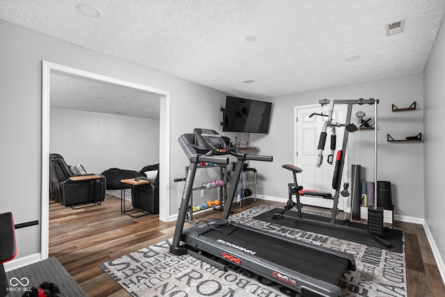 workout room featuring dark hardwood / wood-style flooring and a textured ceiling