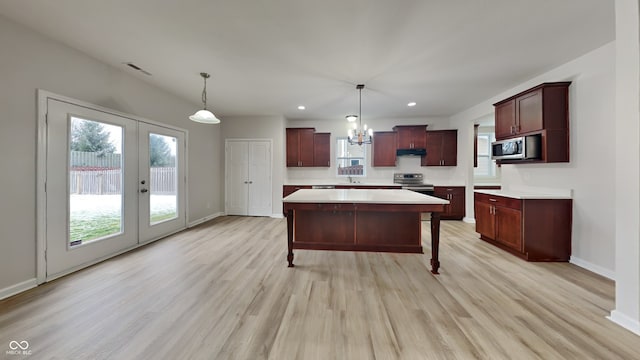 kitchen featuring french doors, hanging light fixtures, appliances with stainless steel finishes, and light hardwood / wood-style flooring