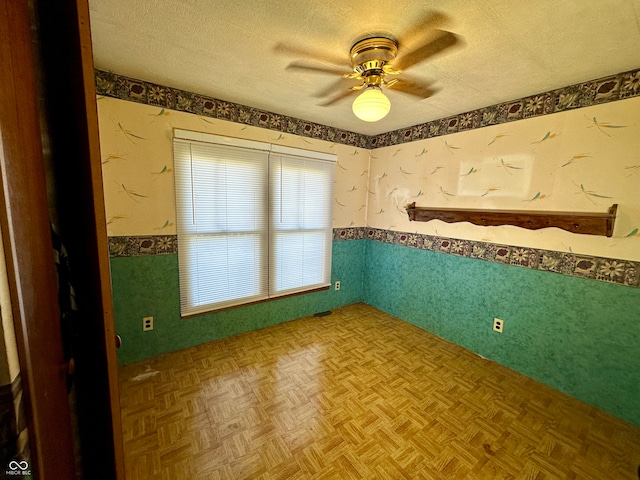 spare room featuring parquet flooring, a textured ceiling, and ceiling fan