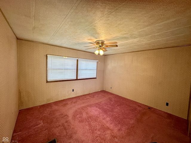 carpeted empty room with ceiling fan and a textured ceiling