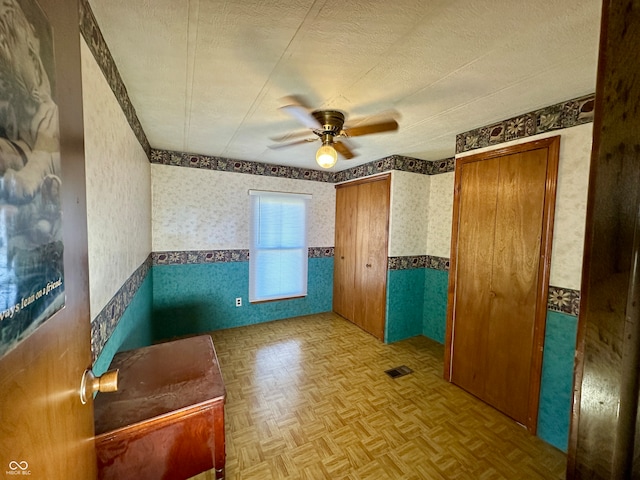 interior space with parquet flooring, a textured ceiling, and ceiling fan