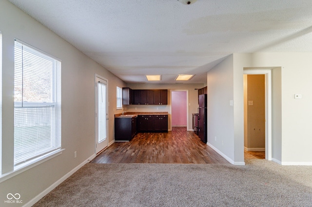 kitchen featuring dark brown cabinets, a textured ceiling, dark hardwood / wood-style floors, and black fridge