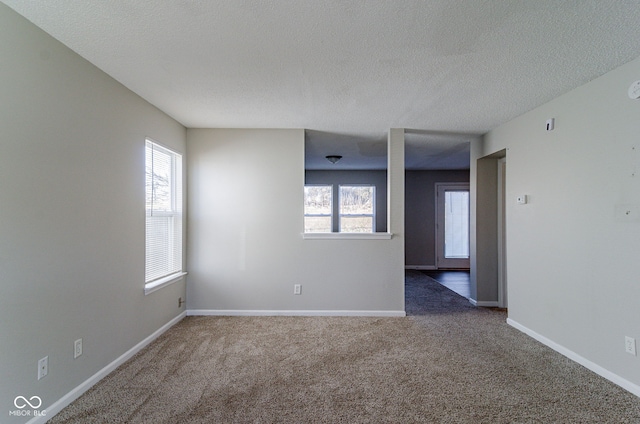 carpeted spare room featuring a healthy amount of sunlight and a textured ceiling