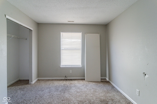 unfurnished bedroom featuring light colored carpet, a textured ceiling, and multiple windows