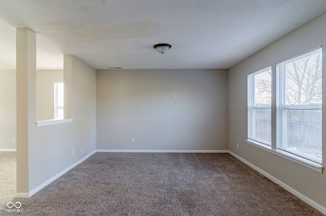 carpeted empty room with a textured ceiling