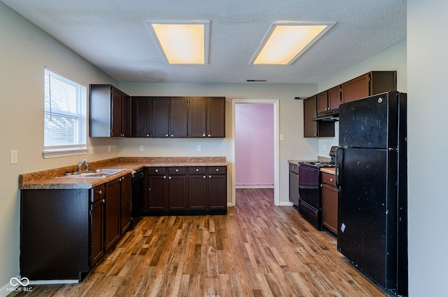 kitchen featuring black appliances, sink, light wood-type flooring, a textured ceiling, and dark brown cabinetry