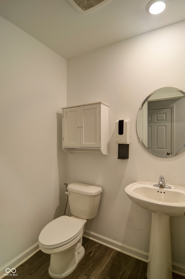 bathroom featuring toilet, wood-type flooring, and sink