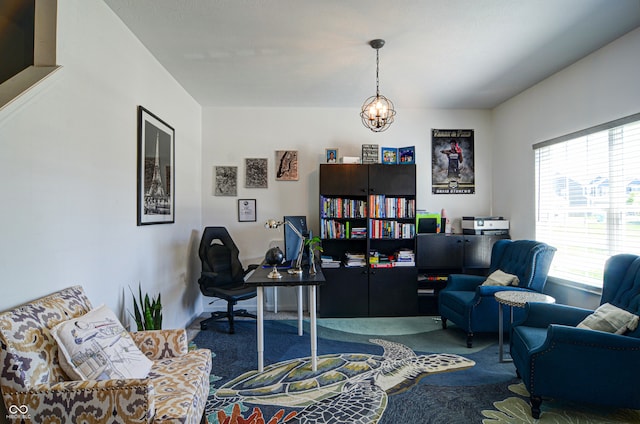 carpeted home office featuring a chandelier