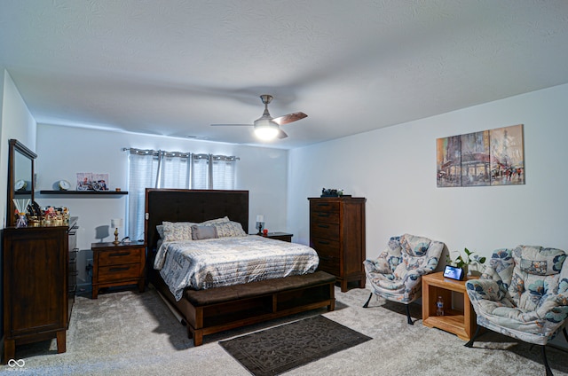 bedroom with ceiling fan, light carpet, and a textured ceiling