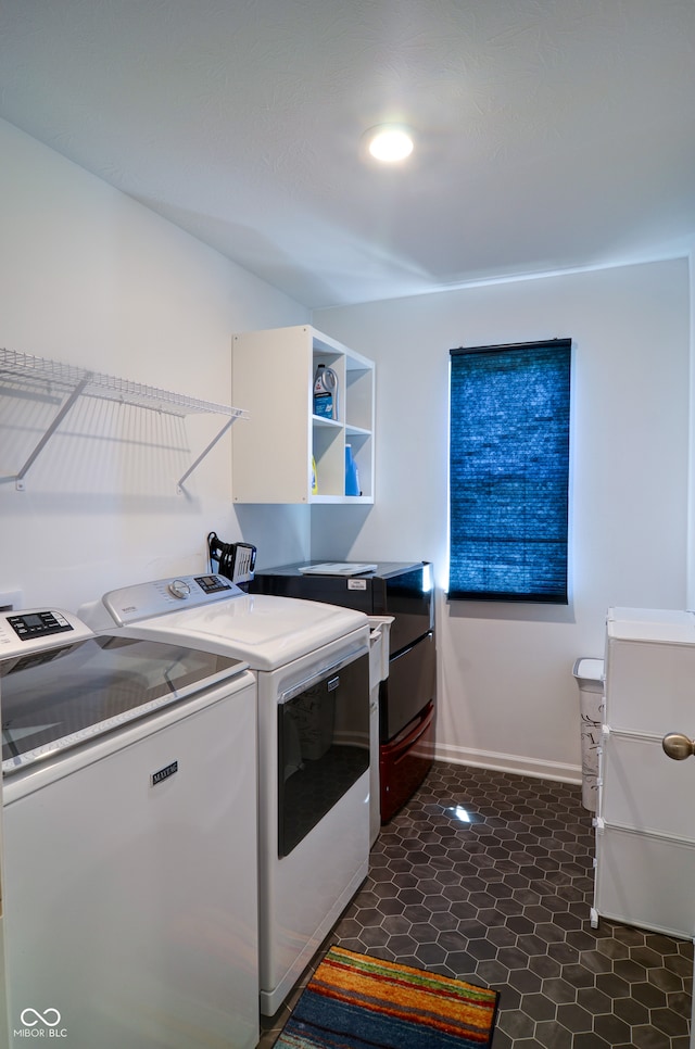 laundry area with cabinets, dark tile patterned flooring, and washing machine and clothes dryer