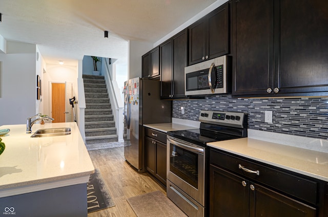 kitchen with light stone counters, light hardwood / wood-style floors, sink, and stainless steel appliances