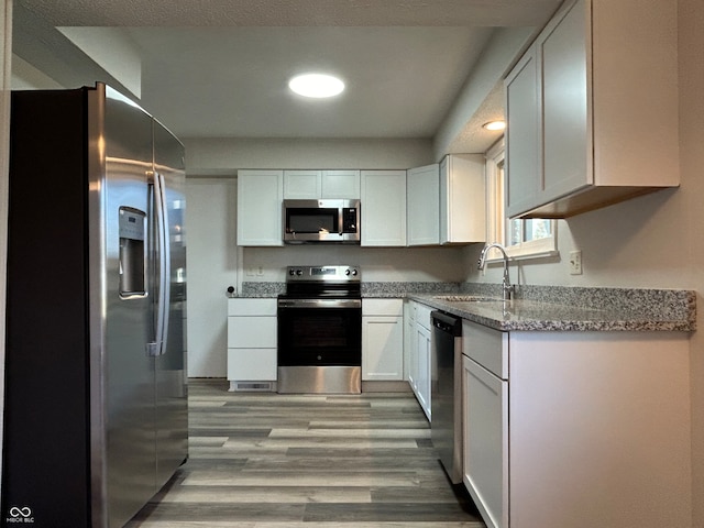 kitchen featuring white cabinets, stainless steel appliances, light hardwood / wood-style floors, and sink