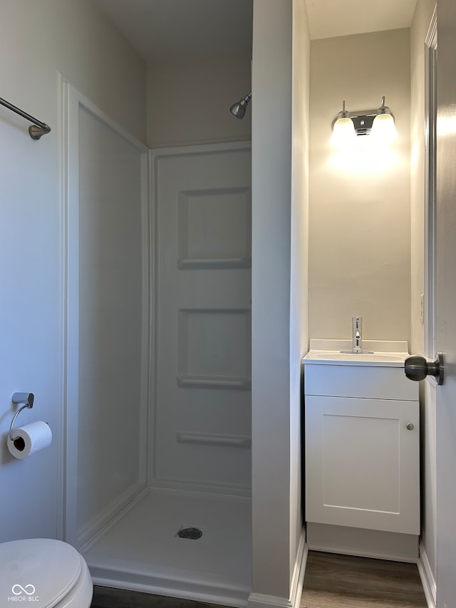 bathroom featuring a shower, toilet, vanity, and hardwood / wood-style flooring