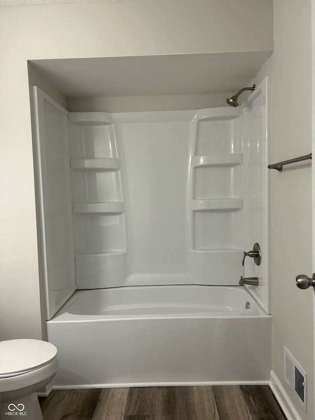 bathroom with shower / bathing tub combination, wood-type flooring, and toilet