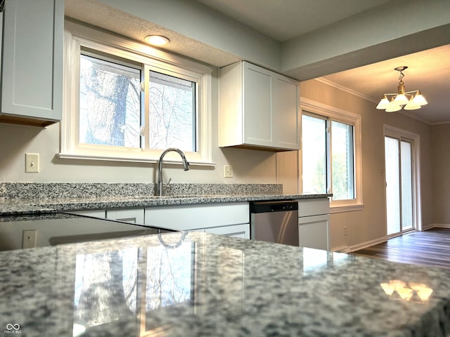 kitchen with light stone countertops, white cabinetry, dishwasher, crown molding, and a chandelier