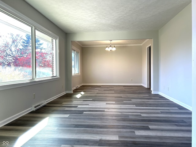 unfurnished room featuring a textured ceiling, dark hardwood / wood-style floors, an inviting chandelier, and ornamental molding