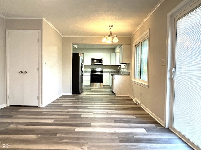 kitchen featuring stainless steel appliances, sink, hardwood / wood-style flooring, an inviting chandelier, and white cabinets