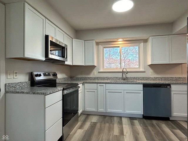 kitchen with hardwood / wood-style floors, white cabinetry, sink, and appliances with stainless steel finishes