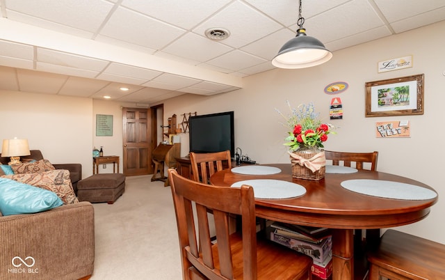 carpeted dining area with a paneled ceiling