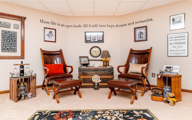 sitting room with a paneled ceiling and carpet floors