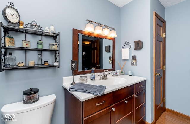 bathroom featuring toilet, hardwood / wood-style flooring, and vanity