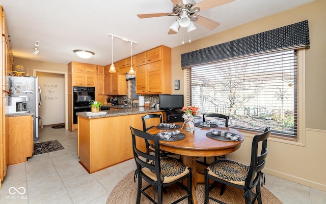 kitchen with stainless steel refrigerator, kitchen peninsula, light tile patterned floors, sink, and black double oven