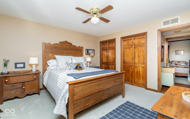 carpeted bedroom with two closets and ceiling fan